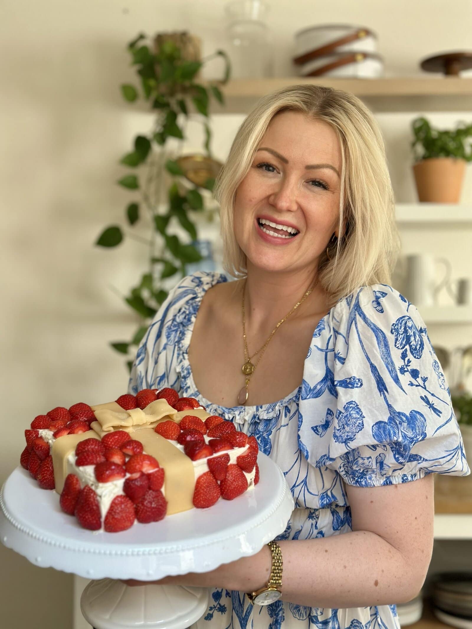 Aurélie mit glutenfreiem Erdbeerkuchen in der Küche Aurélie in ihrer Küche mit einem selbst gebackenen glutenfreien Erdbeerkuchen in der Hand, freundlich lächelnd