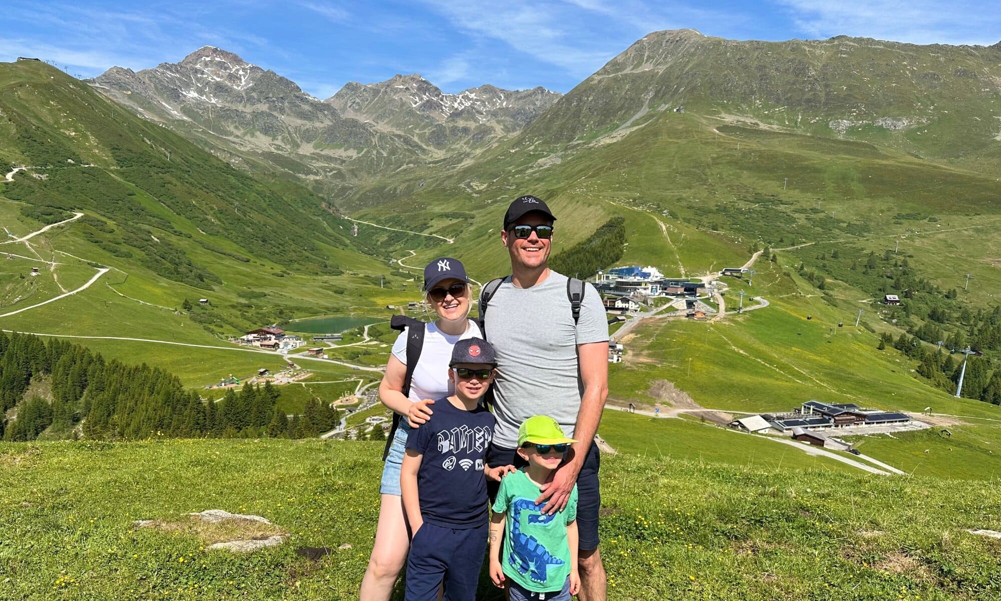 Eine Familie steht gemeinsam vor einer traumhaften Bergkulisse. Alle wirken glücklich und entspannt – ein typisches Urlaubsfamilienfoto.