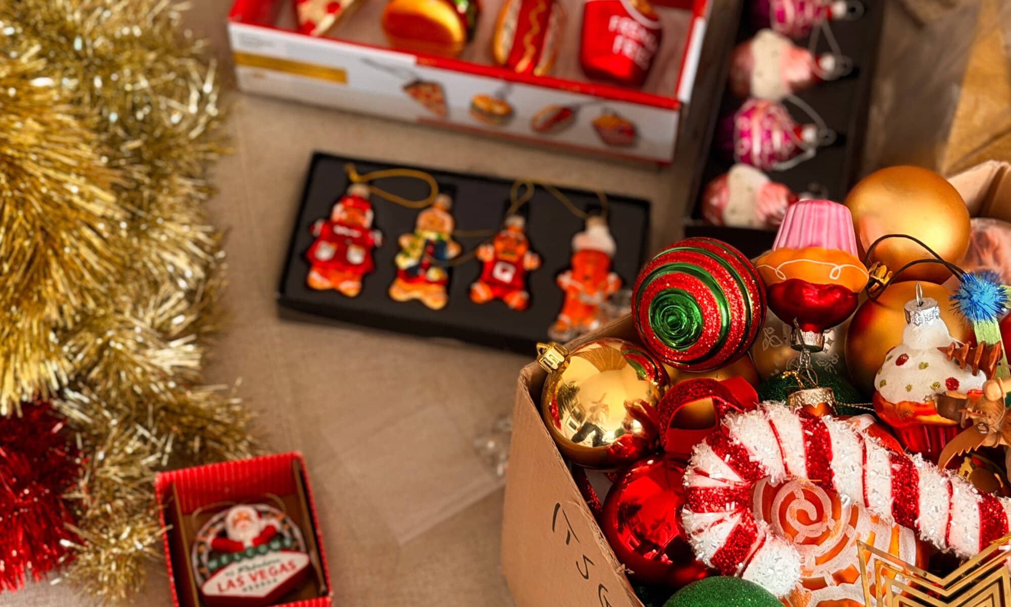 Bunter Weihnachtsbaumschmuck: klassische Kugeln sowie Anhänger in Form von Pommes, Burger und Lebkuchen, dekorativ arrangiert.